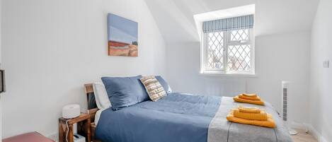 Ein Schlafzimmer mit Bett, Fenster mit Blick, Nachttisch und einer roten Bank.