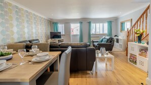 Un salon moderne comprenant un coin repas, un canapé, un téléviseur et un escalier.