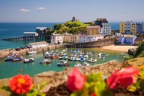 Une ville côtière dotée d’un port de plaisance rempli de bateaux, de bâtiments historiques et d’une statue imposante qui se dresse sur une colline.