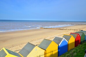 Een strand met kleurrijke strandhutten en helder uitzicht op zee.