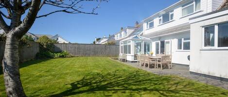 A residential property with a well-maintained lawn, a patio area with outdoor furniture, and a wooden fence.