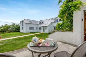 A white house with a paved driveway and a small garden. - 1 Bed in Padstow (oc-p00485) (Saint Merryn)