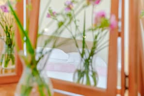 Spiegelbild eines Bettes mit Kissen und einer Vase mit Blumen.