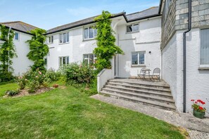 A two-story house with a garden, steps leading to the entrance, and a small outdoor seating area. - 1 Bed in Padstow (oc-p00485) (Saint Merryn)