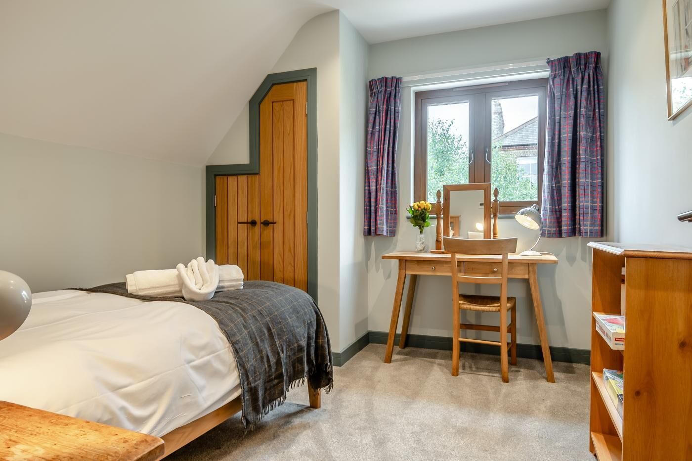 A bedroom with a bed, a desk, a chair, and a wardrobe.