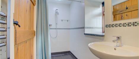 A bathroom with a shower, a sink, and a wooden door.