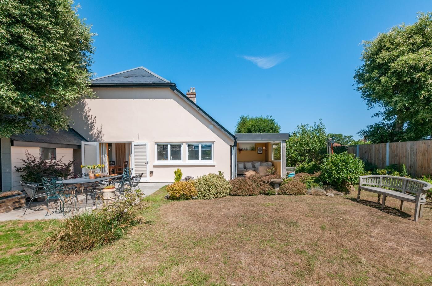 A two-story house with a patio area, a small garden, and a wooden fence.