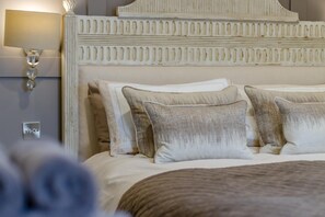 A bedroom with a large bed, a headboard with decorative elements, and a wall-mounted light fixture. - 2 Bed in Conwy (oc-bow273) (Conwy)