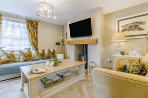 A modern living room with a fireplace, a flat-screen TV, and a sofa with patterned cushions. - 2 Bed in Conwy (oc-bow273) (Conwy)