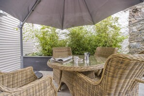 A wicker outdoor seating area with a table, chairs, and a coffee pot.