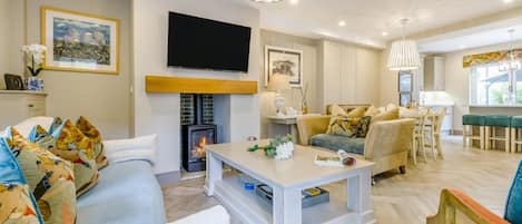 A modern living room with a fireplace, a flat-screen TV, and a dining area with a table and chairs.