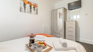 Ein Hotelzimmer mit Bett, Frühstückswagen, Kaffeemaschine, Spiegel und Kleiderschrank.