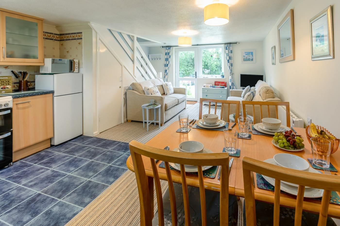 Eine moderne Küche mit Essbereich, einer Treppe und einem Wohnzimmer mit Sofa und Fernseher.