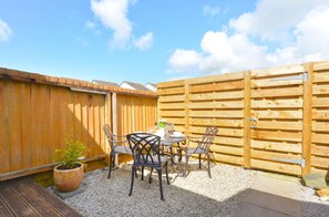 A patio with a table and chairs, a wooden fence, and a potted plant. - 2 Bed in Padstow (oc-p00400) (Padstow)