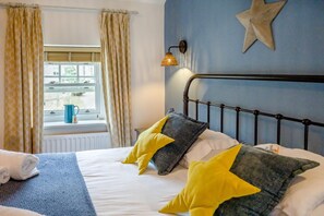 A bedroom with a bed, a window with curtains, a star decoration on the wall, and a lamp. - 2 Bed in Chathill (oc-gd1930) (Ellingham)