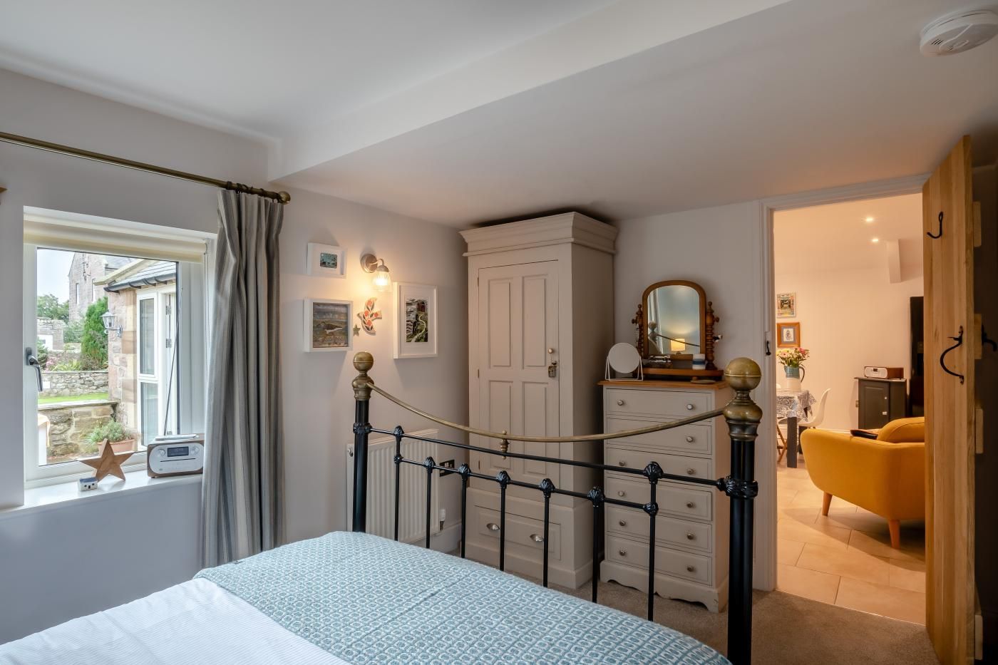 Une chambre à coucher avec un lit, une commode et une vue sur l’extérieur.