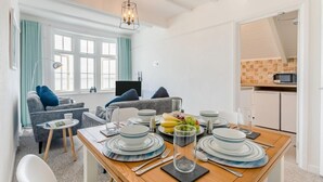 A dining area with a wooden table set for four, surrounded by white chairs. - 2 Bed in St Ives (oc-pc055a) (St Ives)
