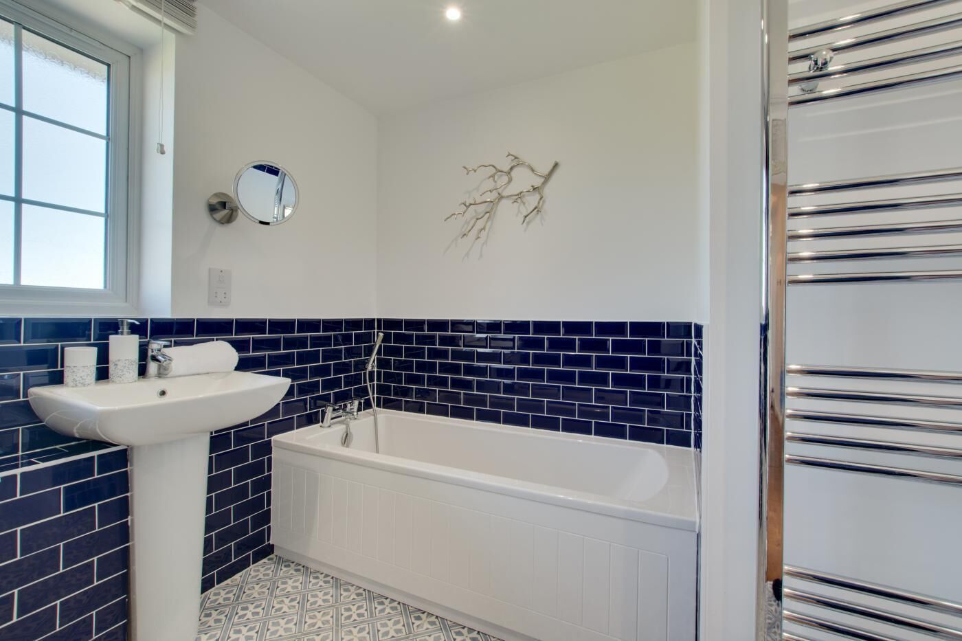 Un baño con lavamanos blanco, bañera y paredes con azulejos azules.