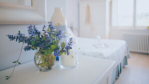 Une chambre à coucher avec un lit, une table de chevet ornée d’un vase de fleurs, une lampe et une fenêtre.