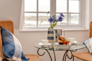 A room with a view of a body of water, a glass table with a vase of flowers, and a plate of pastries. - 3 Bed in Padstow (oc-p00397) (Padstow)