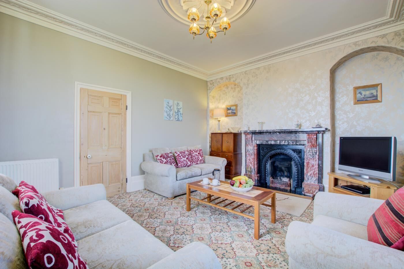 A living room with a fireplace, sofa, coffee table, and television.