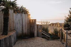 A wooden fence, a palm tree, and a beach view. - 5 Bed in Bexhill-on-Sea (oc-c32704) (Bexhill-on-Sea)