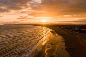 A coastal landscape with a beach, ocean, and a distant town.