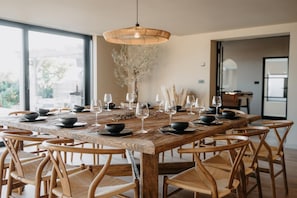 A dining table set with black bowls and wine glasses, surrounded by wooden chairs. - 5 Bed in Bexhill-on-Sea (oc-c32704) (Bexhill-on-Sea)