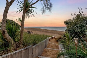 A wooden pathway leading to a beach with a sunset view. - 5 Bed in Bexhill-on-Sea (oc-c32704) (Bexhill-on-Sea)