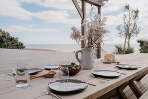 A wooden table set for a meal with a view of the beach and ocean.