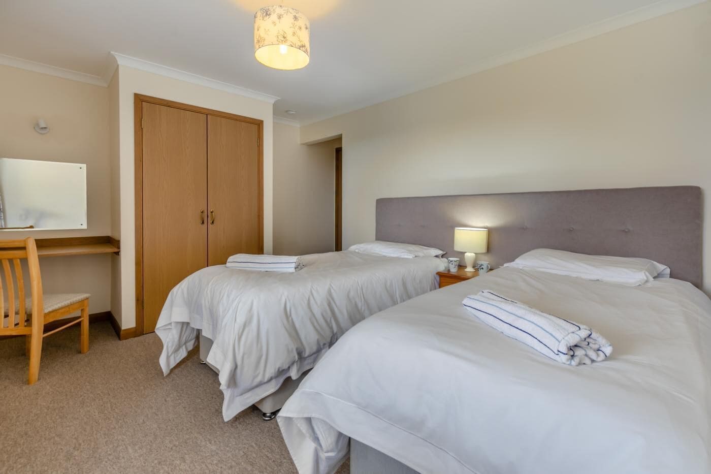 Habitación de hotel con dos camas, un escritorio y un armario.