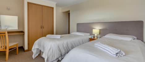 Habitación de hotel con dos camas, un escritorio y un armario.