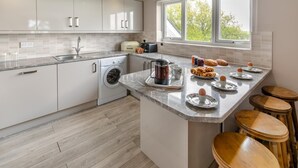 Ett modernt kök med en inbyggd tvättmaskin, en kaffestation och en frukosthörna med ägg och bakverk.