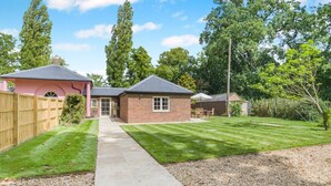 A residential property with a paved driveway leading to a brick house, a fenced yard, and a well-maintained lawn. - 1 Bed in Wymondham (oc-e32664) (Wymondham)