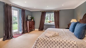 A bedroom with a large bed, a dresser, and a window with curtains. - 1 Bed in Wymondham (oc-e32664) (Wymondham)