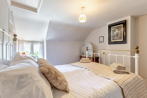 A bedroom with a large bed, a bedside table, a mirror, and a hanging light fixture.