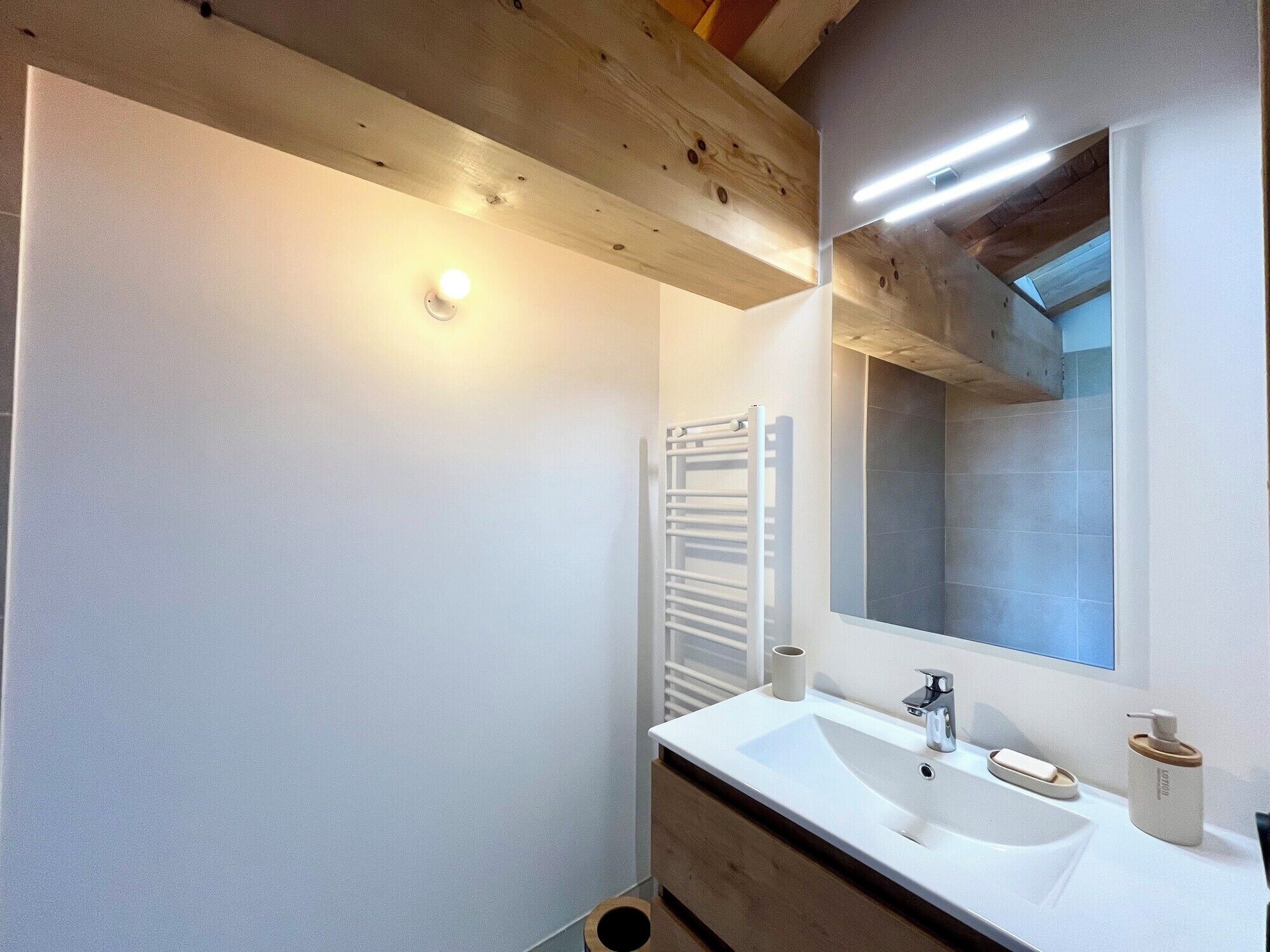A modern bathroom with a white sink, a mirror, and a towel rack.