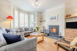 A modern living room with a fireplace, a sofa, a coffee table, and a television. - 3 Bed in Padstow (oc-p00329) (Padstow)