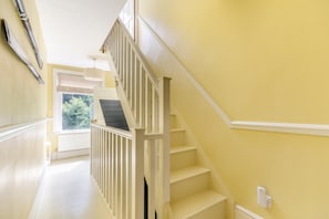 A bright yellow hallway with a white staircase leading to an open door. - 4 Bed in Matlock Bath (oc-r32432) (Matlock Bath)
