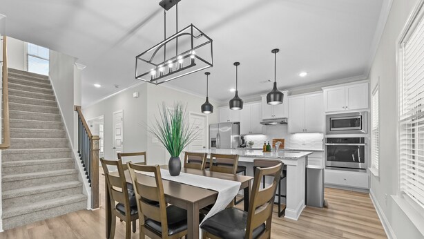 Una cocina moderna con armarios blancos, electrodomésticos de acero inoxidable e iluminación colgante.