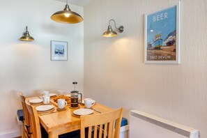 Un coin repas avec une table en bois mise pour le petit-déjeuner, comprenant des assiettes, des tasses et une cafetière.