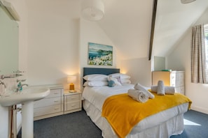 Une chambre d’hôtel avec un lit, une table de chevet avec une lampe, un lavabo et un tableau au mur.