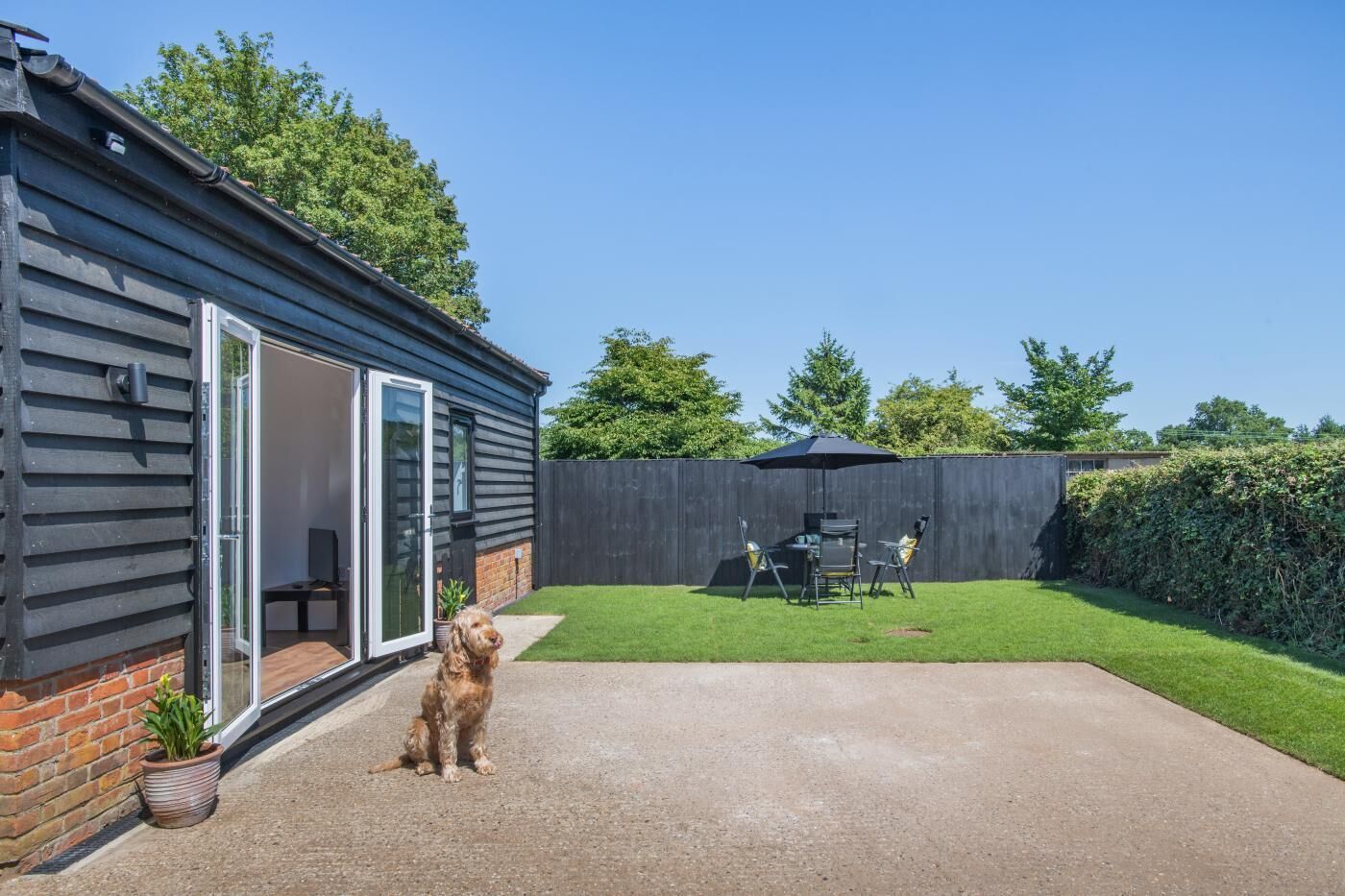A house with a patio, a dog, and a fenced backyard.