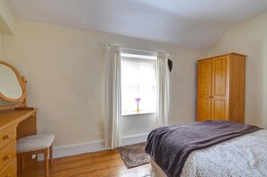 A bedroom with a bed, wooden wardrobe, a desk with a mirror, and a window with curtains. - 2 Bed in Dolgellau (oc-wah671) (Dolgellau)