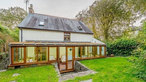 Une maison dotée d’une véranda, d’un escalier en pierre et d’une pelouse bien entretenue.