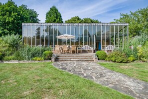 A modern glass house with a stone pathway leading to a patio with outdoor furniture. - 4 Bed in St. Nicholas South Elmham (oc-o32397) (All Saints South Elmham)
