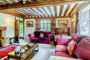 A cozy living room with a fireplace, a sofa, a coffee table, and a window with curtains. - 4 Bed in St. Nicholas South Elmham (oc-o32397) (All Saints South Elmham)