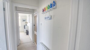 Un couloir avec un radiateur, un panneau indicateur et une rangée de décorations colorées en forme de maisons accrochées au mur.