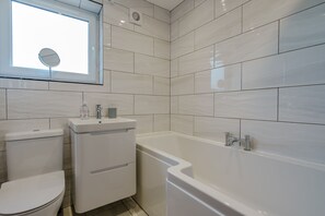 A modern bathroom with a toilet, sink, and bathtub. - Rothwill House | Stylish Dog Friendly Apartment Near the Beach (Winterton-on-Sea)