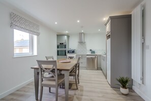 A modern kitchen with white cabinets, a built-in oven, and a microwave. - Rothwill House | Stylish Dog Friendly Apartment Near the Beach (Winterton-on-Sea)